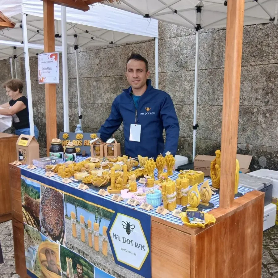 Simão na sua banca de feira, com mel e vários modelos de velas